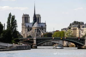Paris, France. View from a boat on the river Seine. Passing the Notre Dame cathedral. Pont de Sully bridge in the foreground.